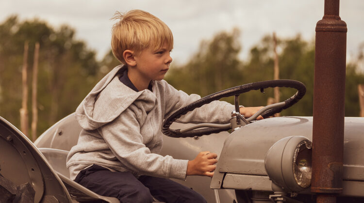 Bild på en pojke som blir fotograferad på en traktor.